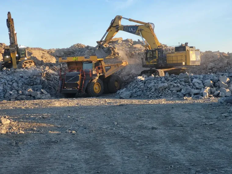 Excavator loading a dump truck at a quarry